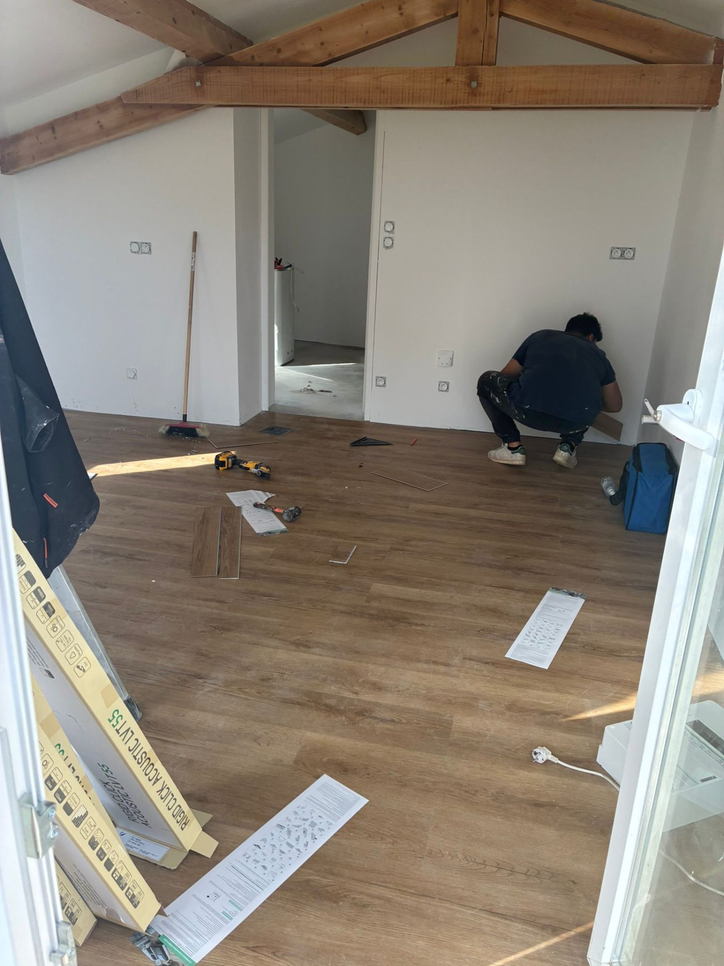 Pose de parquet sous charpente apparente en cours de chantier